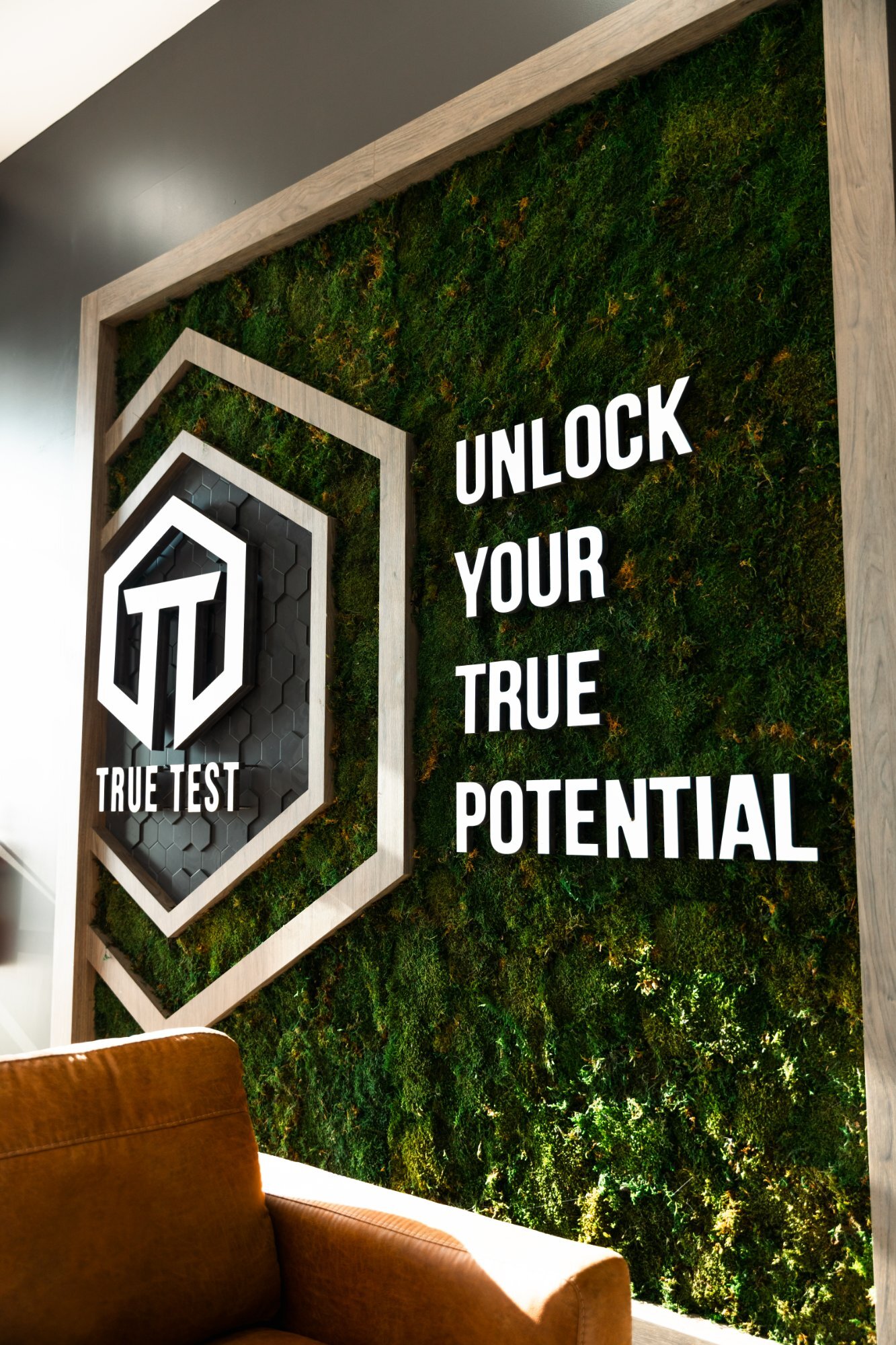 True Test moss wall with the logo and “Unlock your true potential”