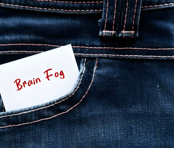 Note reading “Brain Fog” tucked into a denim pocket, illustrating menopause brain fog.