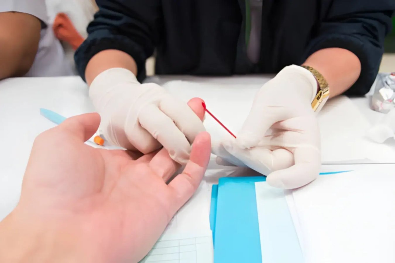 Healthcare professional collecting a fingertip blood sample for hematocrit monitoring during TRT.