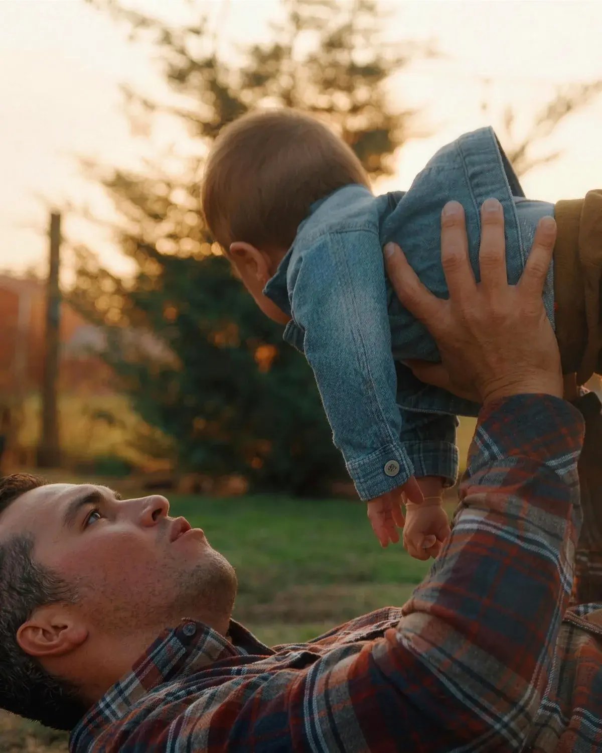 A father lifting his young child overhead at sunset