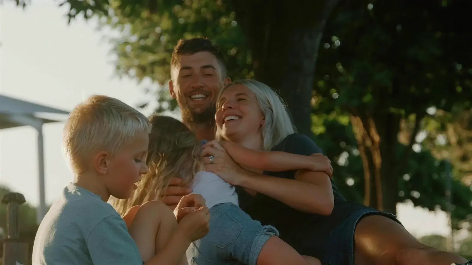 A family laughing together on the grass at golden hour